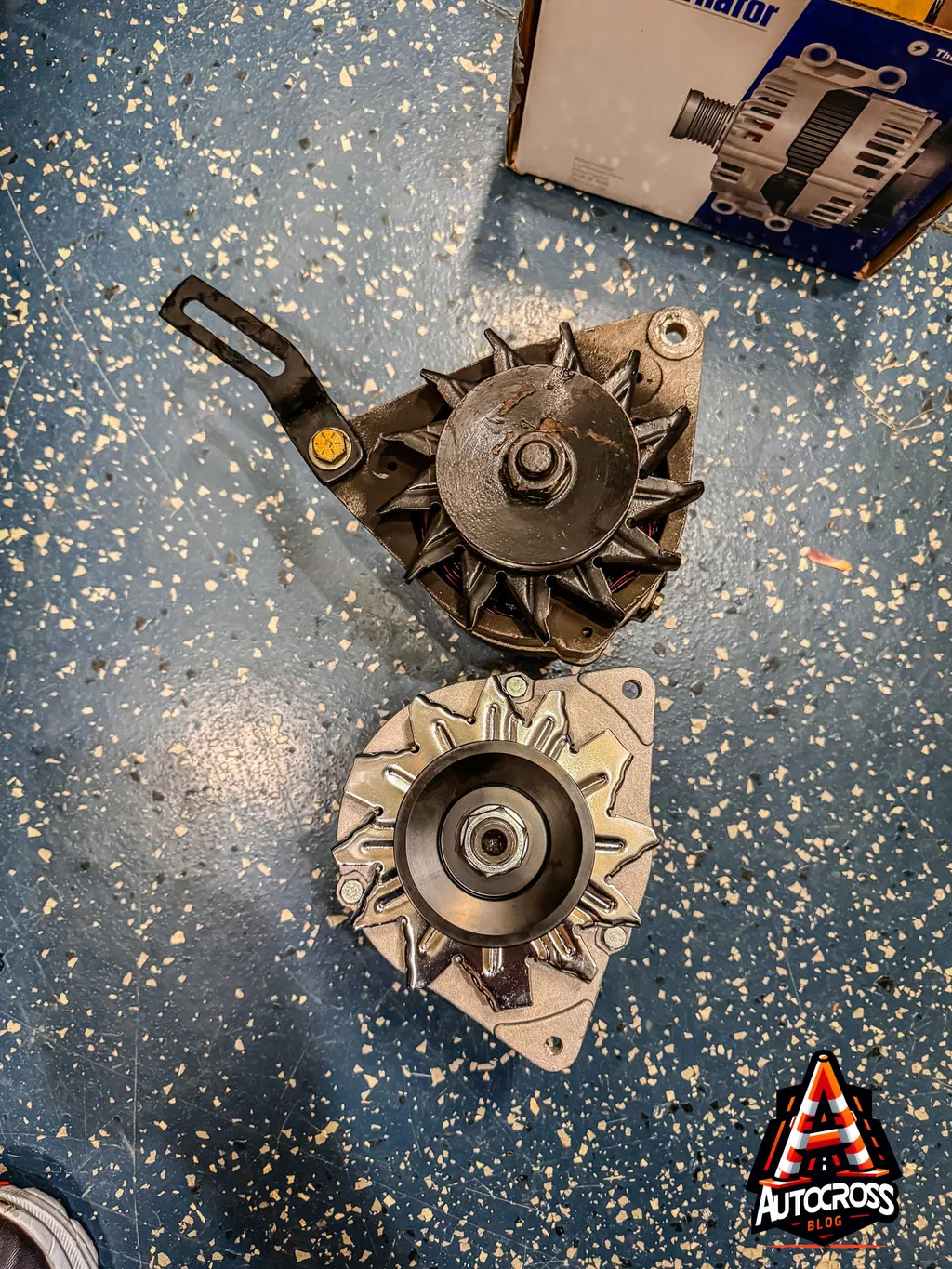 Old and New alternator sitting on the garage floor Old and New alternator sitting on the garage floor